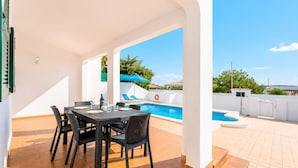 Une terrasse extérieure avec une piscine, une table et des chaises, et une vue sur le paysage environnant.