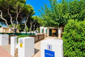 Une villa nommée « Villa Estrella », dotée d’une allée dallée, d’une clôture en bois et d’une végétation luxuriante.