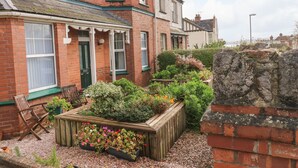 A residential area with brick houses, a garden with raised beds, and a wooden bench. - Tidal Reach (Paignton)