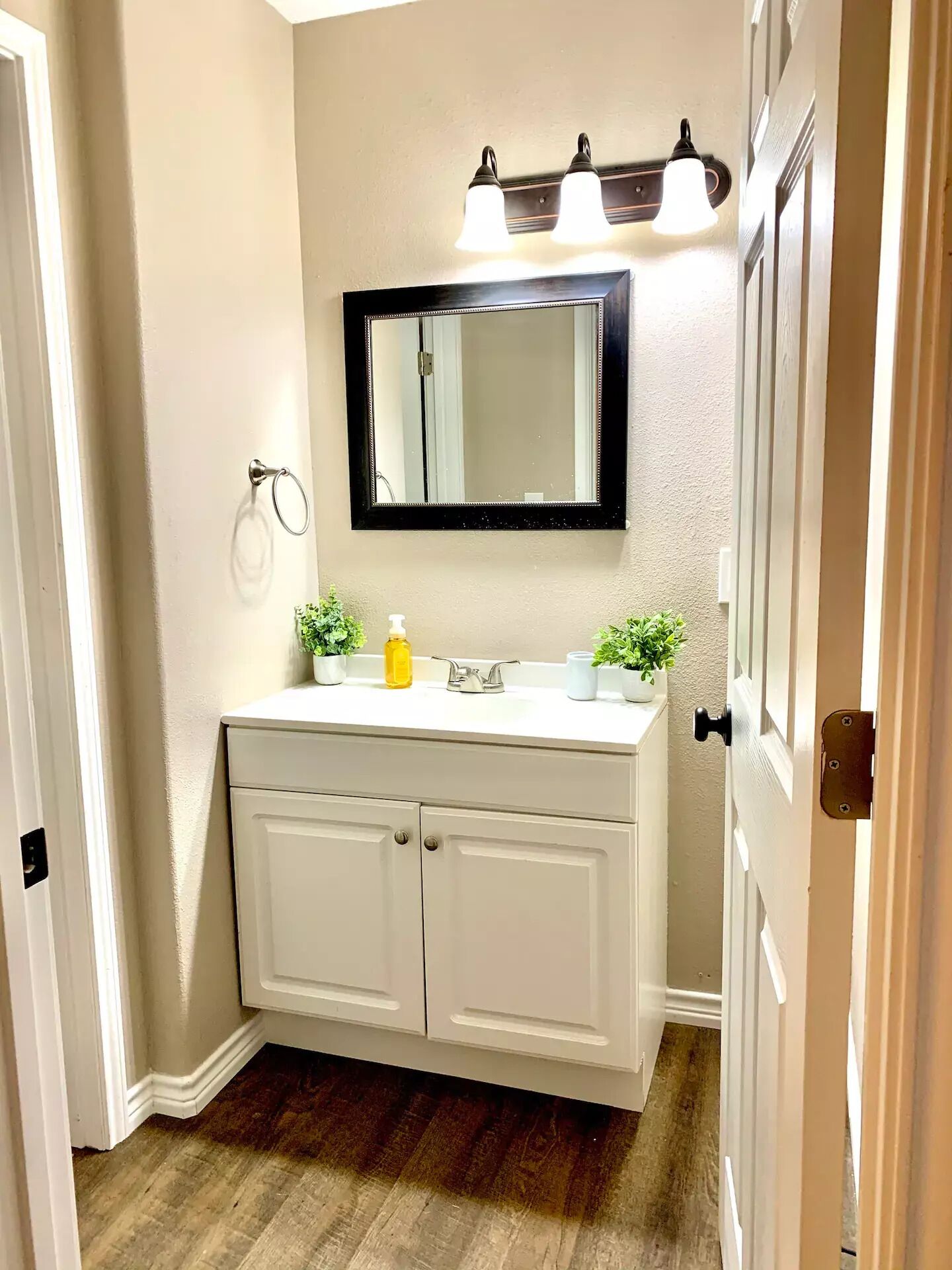 A bathroom with a white vanity, a mirror, and two wall-mounted lights.