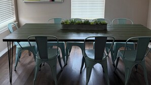 A dining area with a long table, six chairs, a potted plant, and a painting on the wall. - TRANQUILITY BAY-Spring /Summer /WINTER TEXAN FAVORITE!!  Come RELAX with us! (Aransas Pass)