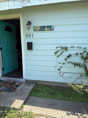 Uma casa com porta verde, caixa de correio e placa com a inscrição 'Tranquility Bay 501'.