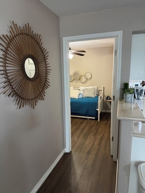 Quarto com cama, espelho fixado na parede e um objeto decorativo circular.