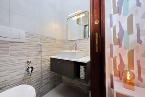 A modern bathroom with a white sink, a mirror, and a shower.