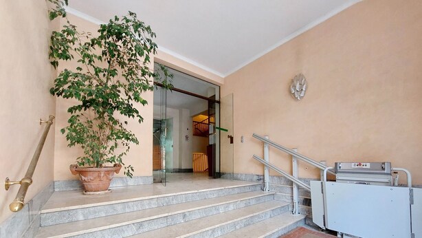 A set of marble stairs leading to a room with a glass door, a potted plant, and a white elevator. - Comfy apartment next to Vatican city (Roma)