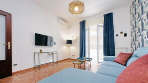 A modern living room with a sofa, a small table, a TV mounted on the wall, and a patterned wall. - Comfy apartment next to Vatican city (Roma)