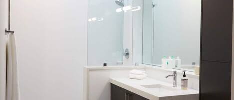 A modern bathroom with a skylight, white tiles, a large mirror, and a white sink.