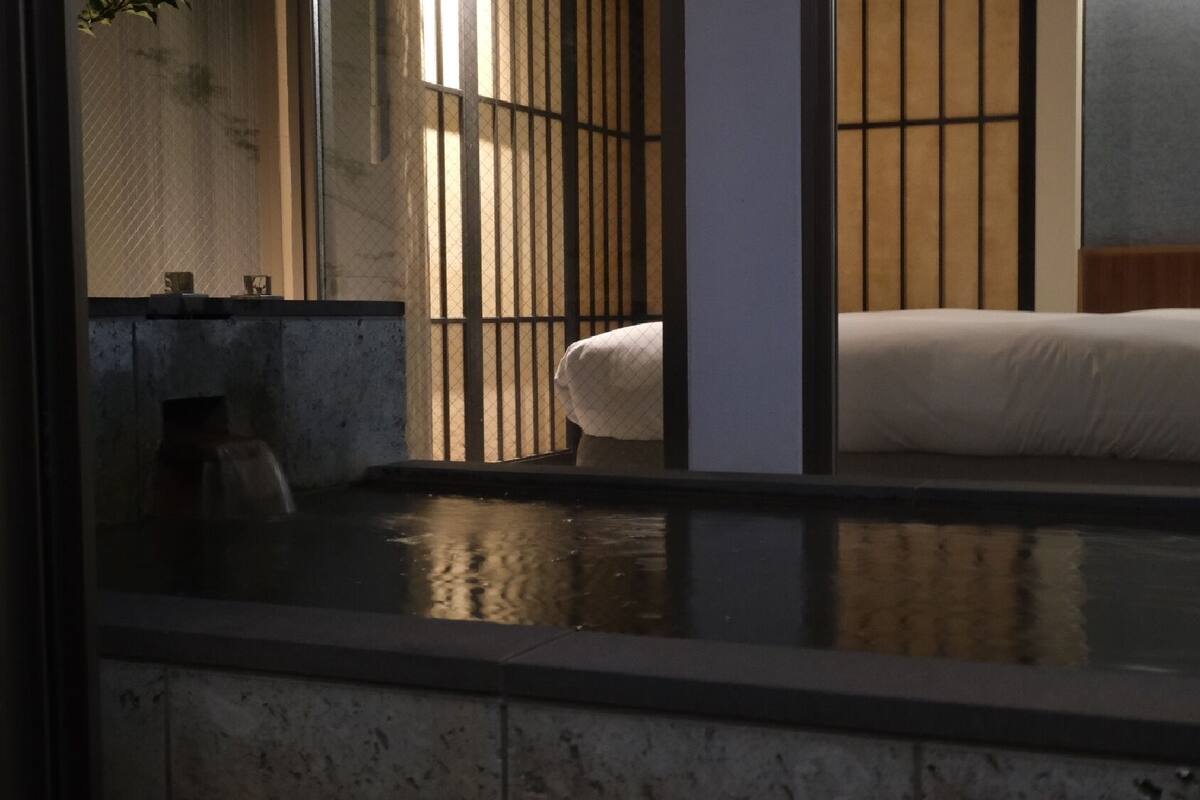 Quarto tradicional em estilo japonês, com piso de tatame, mesa de madeira baixa e um painel de correr shoji.