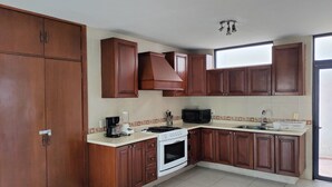 A kitchen with wooden cabinets, a stove, a microwave, and a coffee maker.