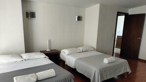 A hotel room with two beds, a nightstand, a mirror, and a wooden floor.