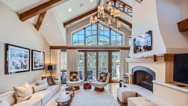 A spacious living room with a high ceiling, large windows, a fireplace, and a cozy seating area.