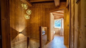 A wooden interior with a staircase leading to a bedroom with a window.