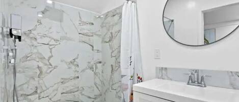 A bathroom with a shower, a sink, and a mirror.