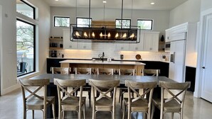 Une cuisine moderne dotée d’un îlot central, de meubles blancs et d’un coin repas avec des chaises en bois.
