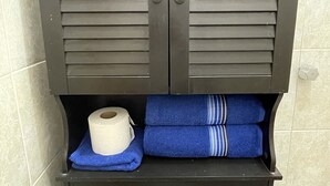 A bathroom with a dark wooden cabinet, a toilet, and towels.