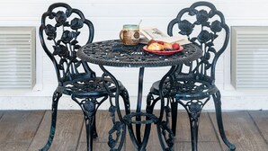 A small outdoor table with two chairs, a jar, a book, and a plate with food.