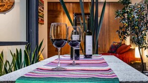Una mesa con dos copas de vino y una botella, sobre un mantel a rayas de colores.