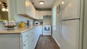 A kitchen with white cabinets, a microwave, an oven, and a refrigerator.
