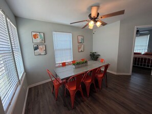 A dining area with a wooden table, red chairs, a ceiling fan, and artwork on the walls. - TEQUILA SUNRISE - A Summer & WINTER TEXAN FAVORITE! Come relax with us. (Aransas Pass)