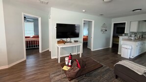A modern living room with a flat-screen TV, a coffee table with a fire extinguisher, and a sofa.