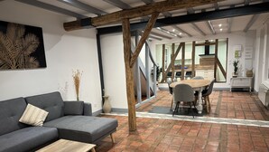 Un salon moderne avec un canapé gris, une table basse en bois et un coin repas comprenant une table et des chaises en bois.