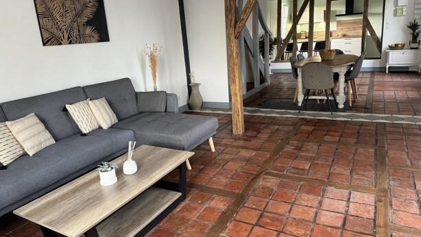 Un salon moderne avec un canapé gris, une table basse en bois et un sol en briques.