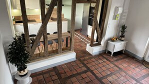 Une pièce dotée d’une structure en poutres apparentes, d’une table à manger avec des chaises, d’une armoire blanche et d’une plante en pot.