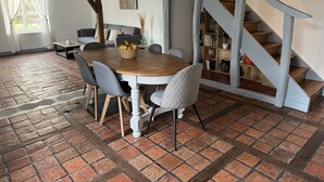 Un coin repas avec une table en bois, des chaises grises et un panier de fruits.