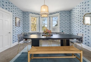 A dining area with a black table, wooden bench, and patterned chairs. - Jungle Retreat! Parking/Yard/Wine/Firepit (Baltimore)