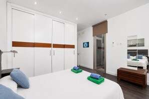 Ein Schlafzimmer mit Bett, Kleiderschrank, einer Sitzbank und einer Dusche.
