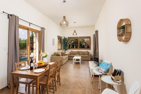 A spacious living area with a dining table, two sofas, and a TV. - Villa Windmill - Three Bedroom Villa, Sleeps 6 (Poli Crysochous)