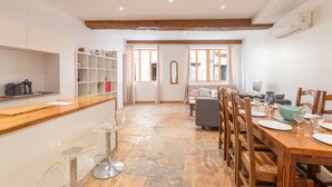 A spacious kitchen with a wooden countertop, a dining area with a table set for four, and a cozy seating area with a sofa and chairs.