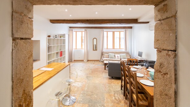 A spacious kitchen with a wooden countertop, a dining area with a table set for two, and a cozy seating area with a sofa and armchairs.