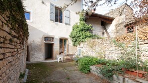 A rustic courtyard with stone walls, a wooden table, and chairs.