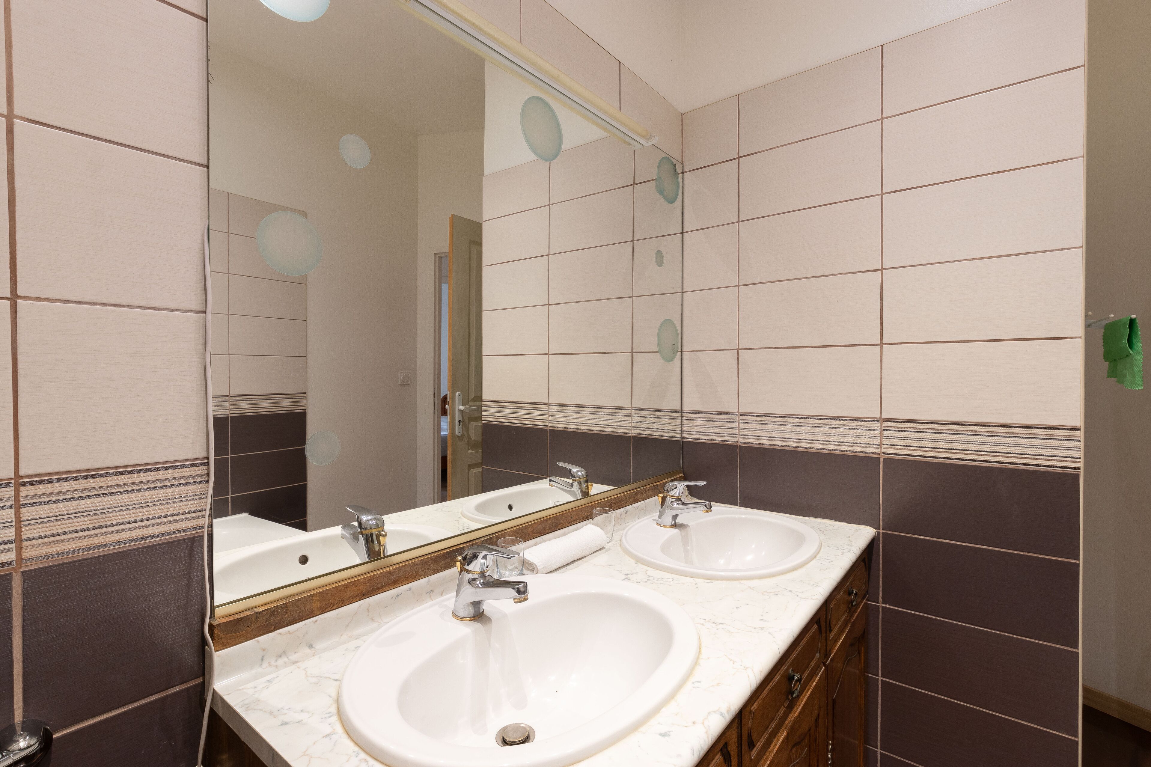 A bathroom with two sinks, a mirror, and a towel rack.