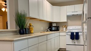 Une cuisine moderne avec des meubles blancs, un four à micro-ondes, une cuisinière et un évier.
