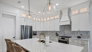 A modern kitchen with white cabinetry, a large island, stainless steel appliances, and pendant lighting. - Luxe 5BR with Pool, Hot Tub, Outdoor Kitchen, Bikes, Close to Beach & Seaside (Santa Rosa Beach)