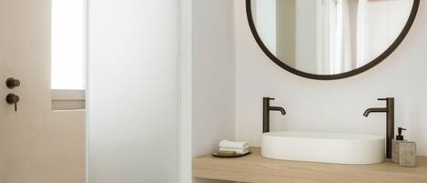 A bathroom with a round mirror, two sinks, and a towel rack.