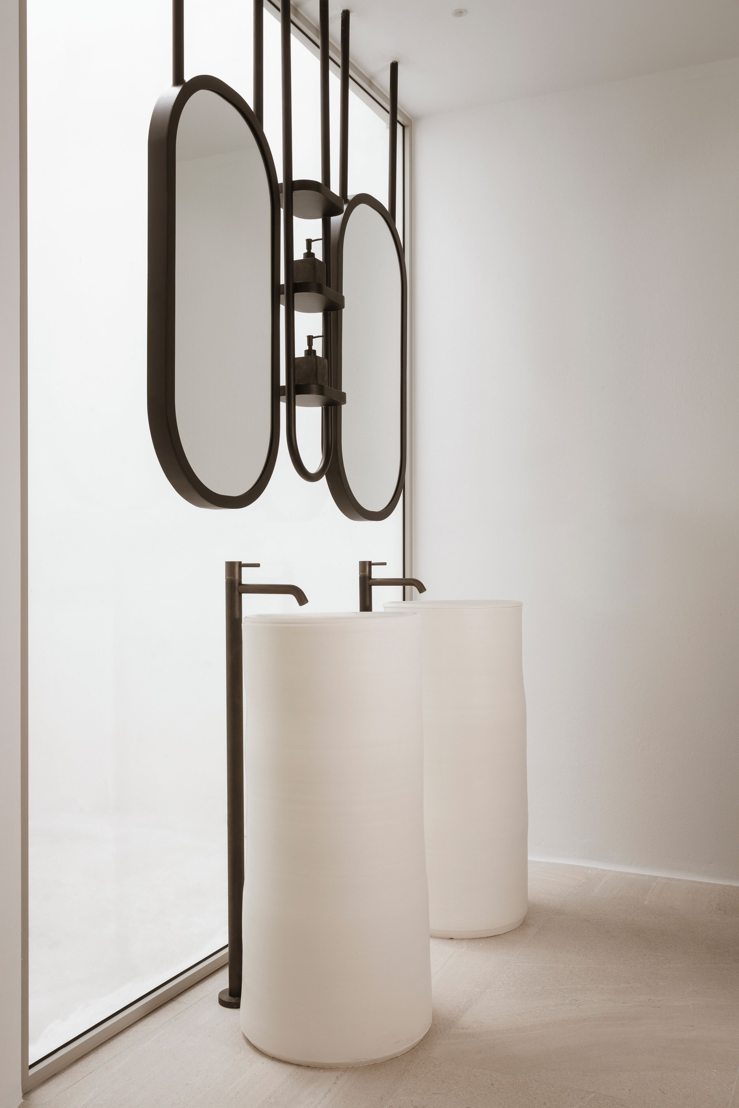 Een moderne badkamer met een grote spiegel, twee ronde wasbakken en een minimalistisch design.