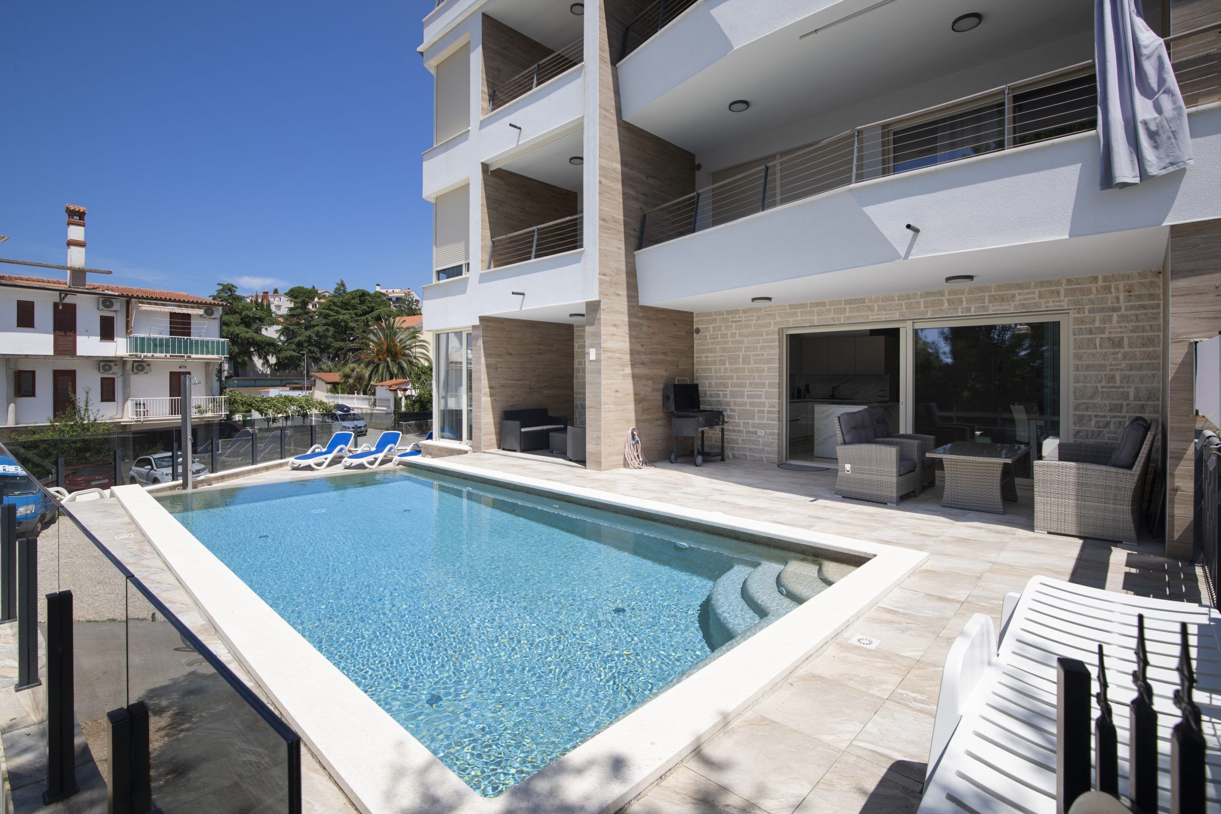 Un hotel moderno con piscina, mobiliario exterior y vistas del entorno.