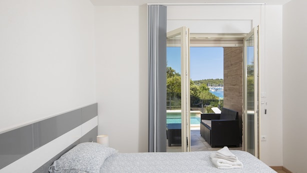A bedroom with a bed, a nightstand, and a view of an outdoor pool area.