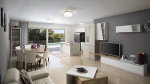 A modern living room with a sofa, coffee table, and TV. There is a dining area with a table and chairs, and a kitchen with a refrigerator and stove.