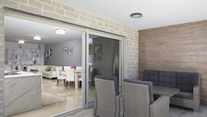 A modern living space with a kitchen, dining area, and a seating area with wicker furniture.