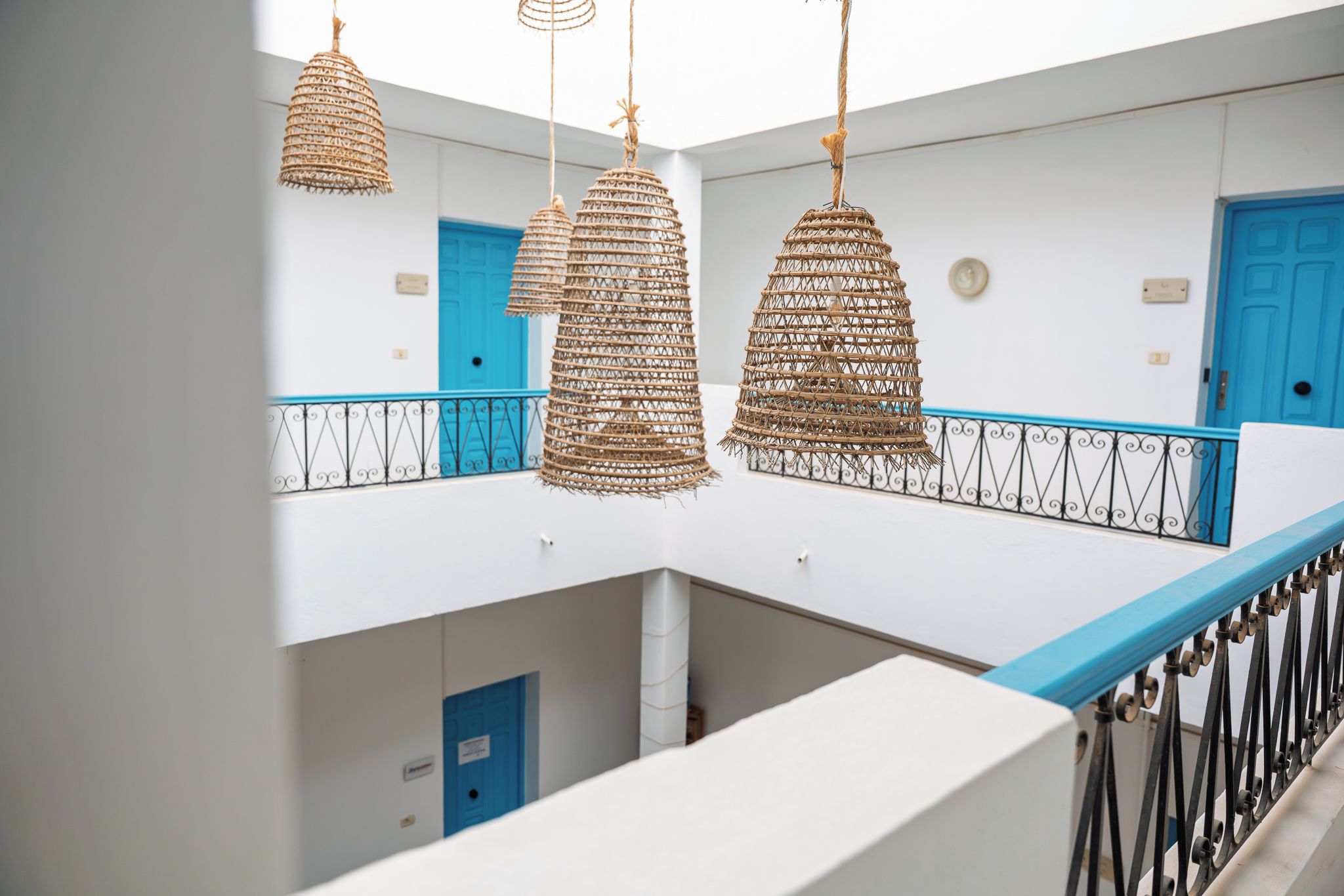 A modern interior with a white and blue color scheme, featuring a balcony with a railing and hanging wicker lamps.