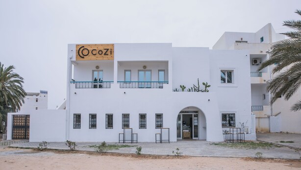 A two-story building with a sign reading "CocoZi" on the upper level. - Cozi Coliving (Mezraia)
