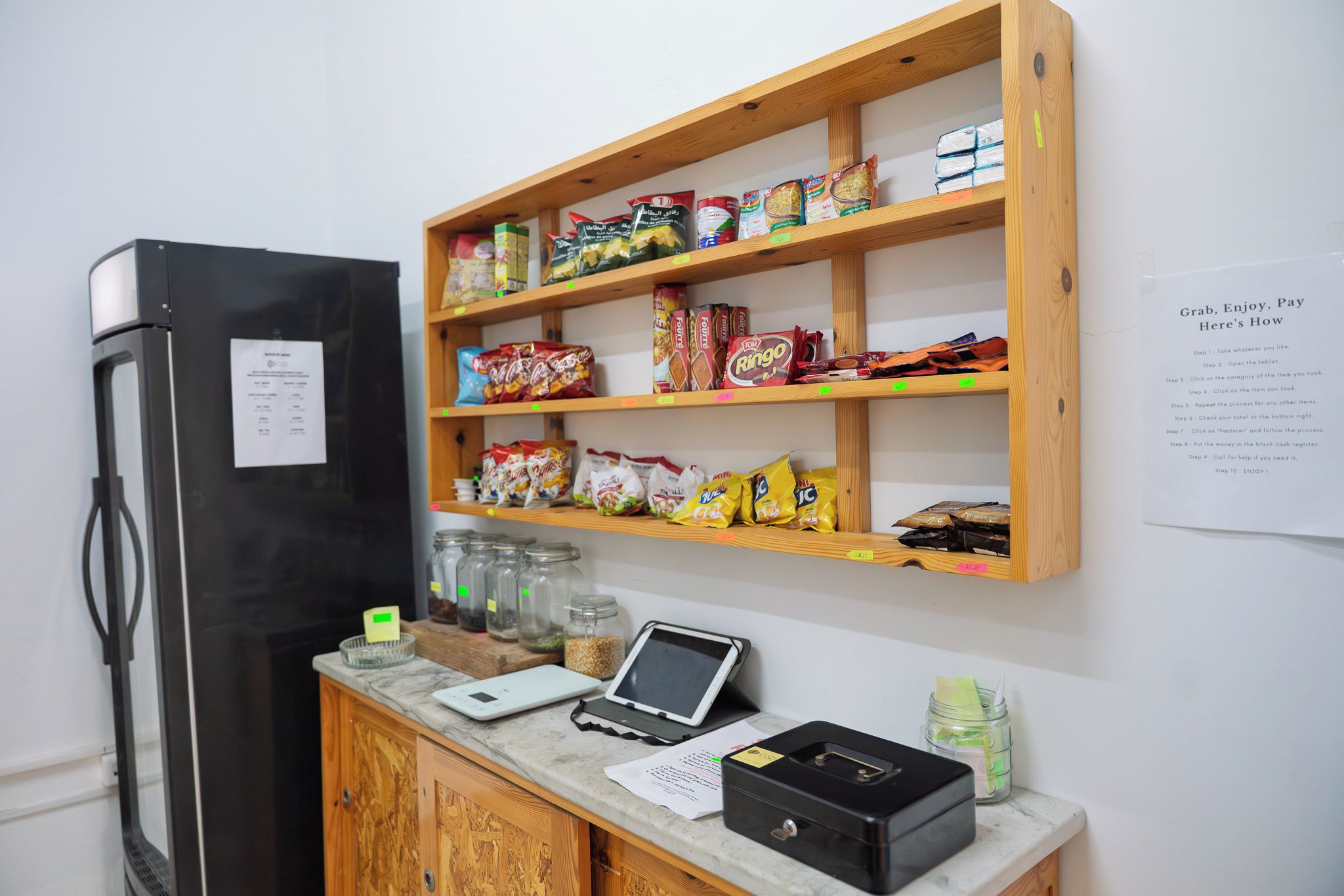 Balcão de atendimento com diversos snacks e um tablet digital.