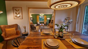 Zona pranzo con tavolo in legno apparecchiata per due persone, una sedia e una bottiglia di vino.
