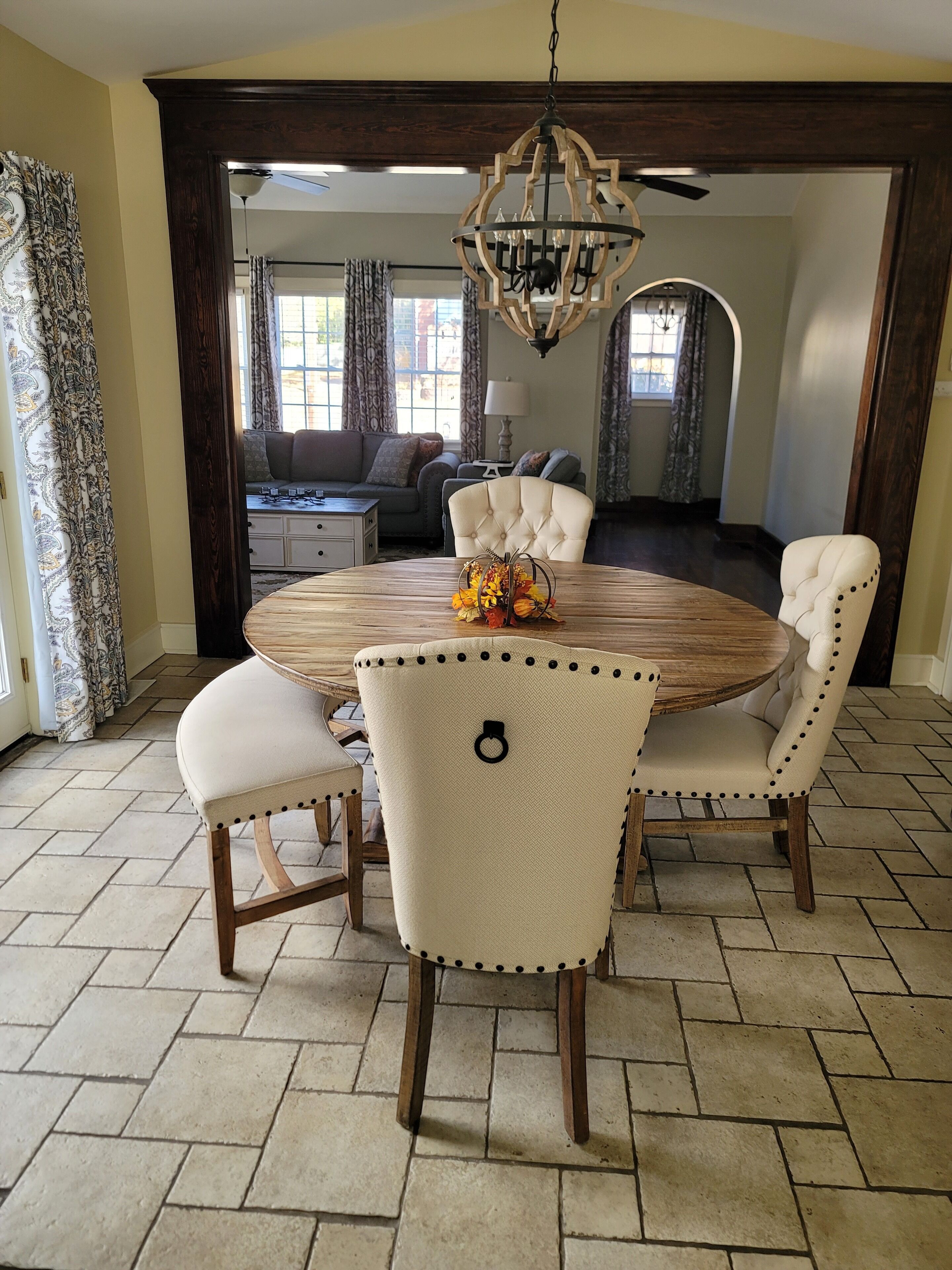 A dining area with a round wooden table, four upholstered chairs, and a decorative centerpiece.