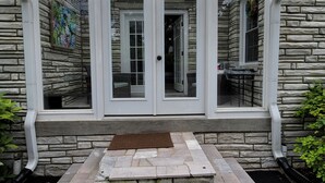 A stone house with a covered porch, a front door, and a small outdoor seating area.