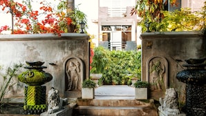 A stone staircase leading to a gated entrance with statues and a fountain.